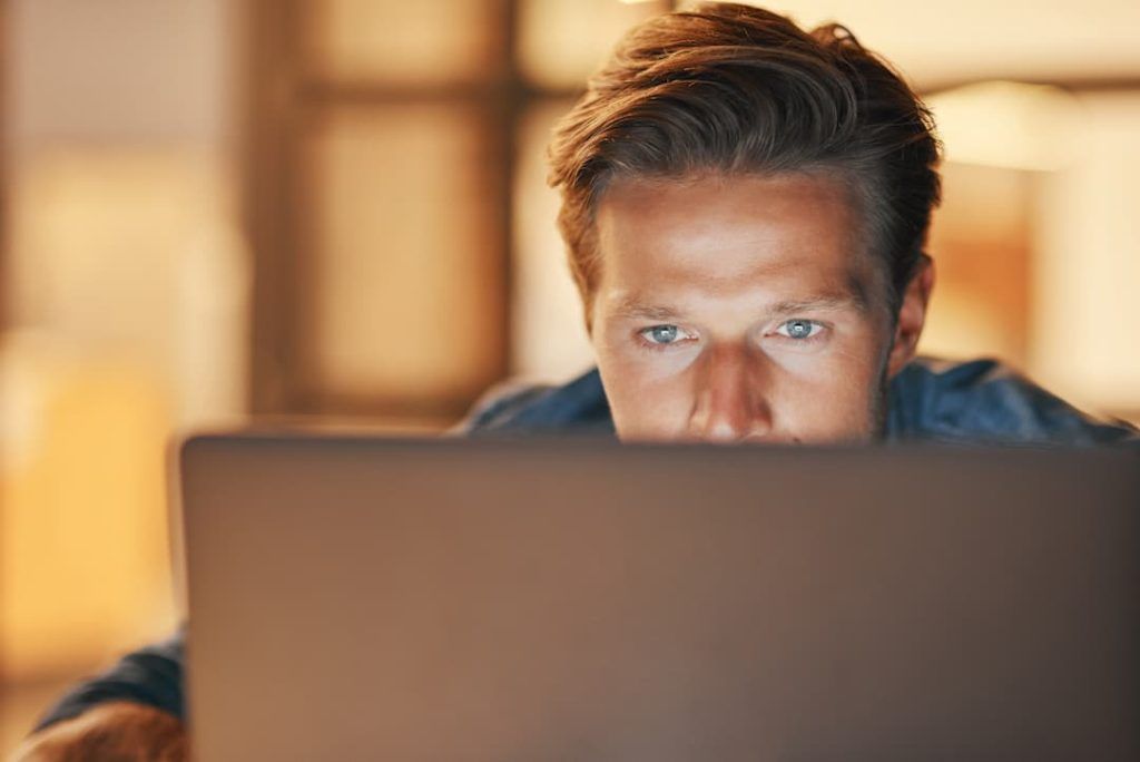 Man Sat Behind A Laptop Screen