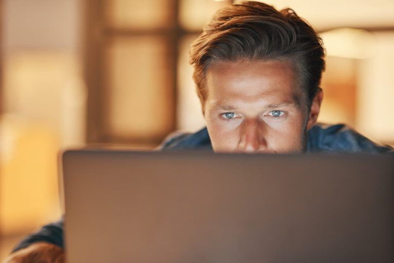 Man Sat Behind A Laptop Screen